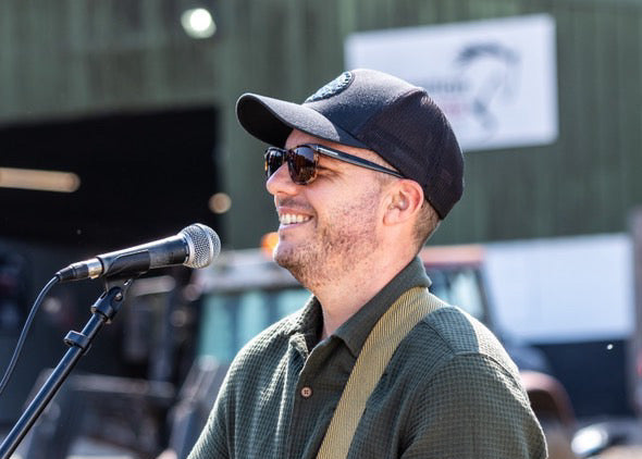 Man playing guitar and singing into a microphone outdoors.